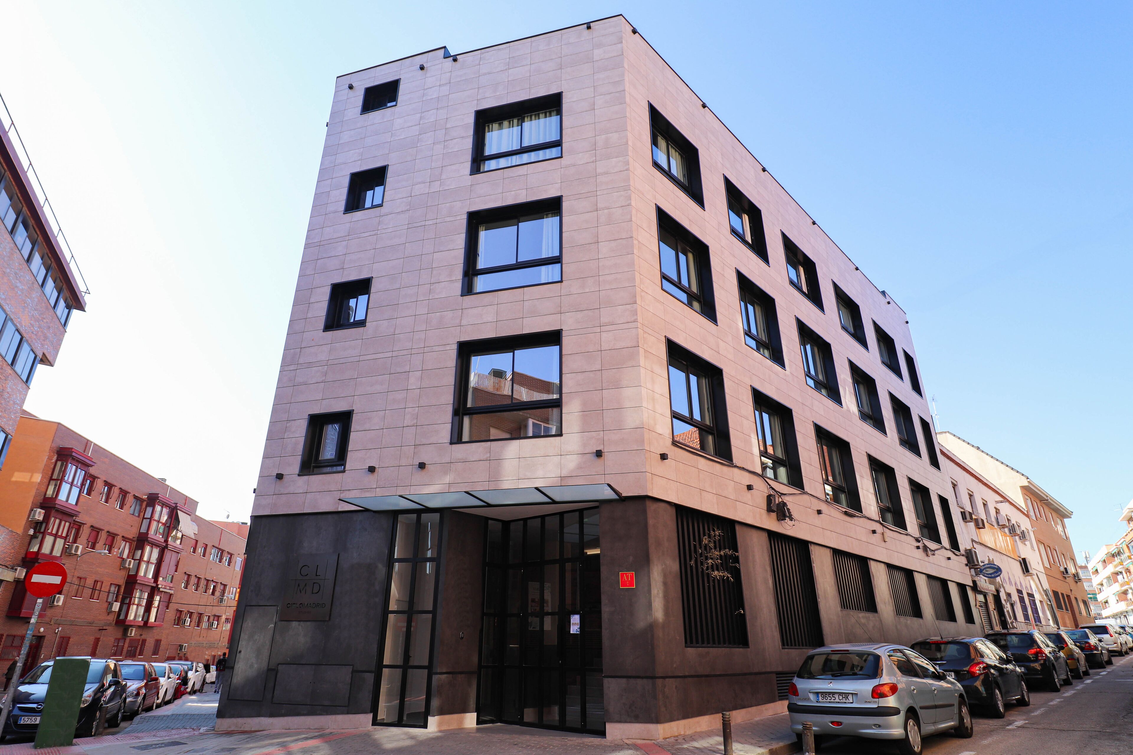 Un edificio de varios pisos con diseño moderno, que cuenta con una entrada de cristal y un letrero que indica espacio para negocios u oficinas.