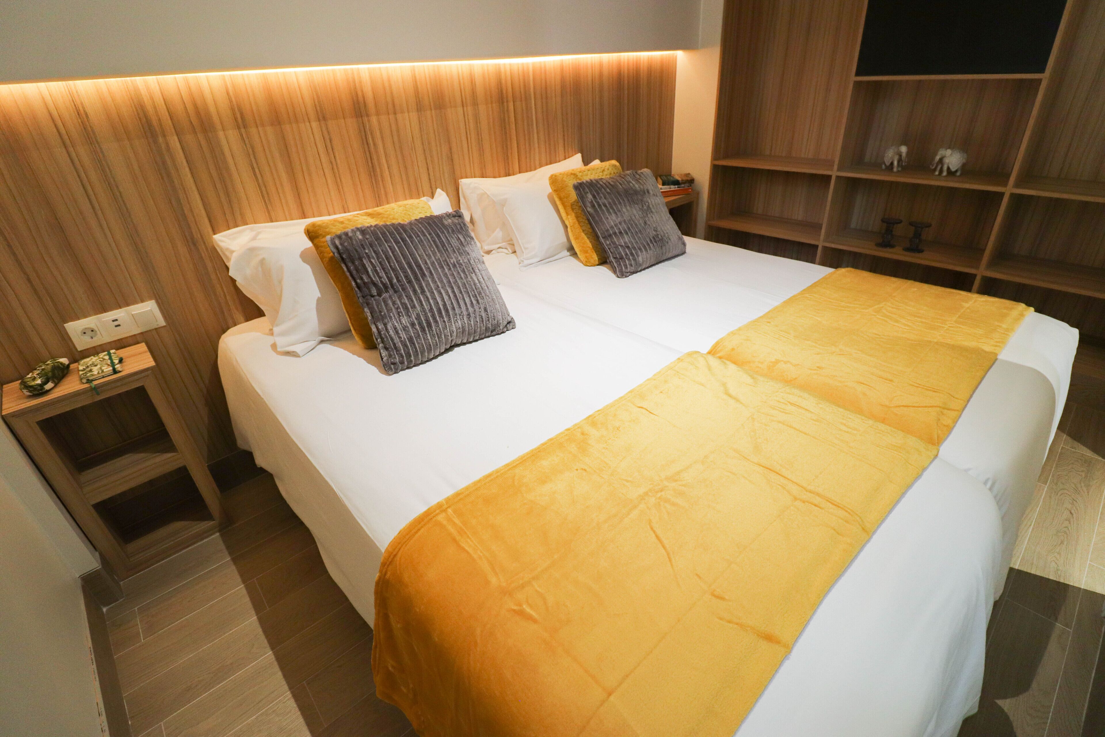 A hotel room with a large bed, wooden headboard, and a nightstand with a lamp.