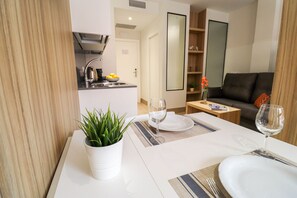A dining area with a table set for two, a potted plant, and a kitchen in the background. - CIELO Madrid Studios (Madrid)