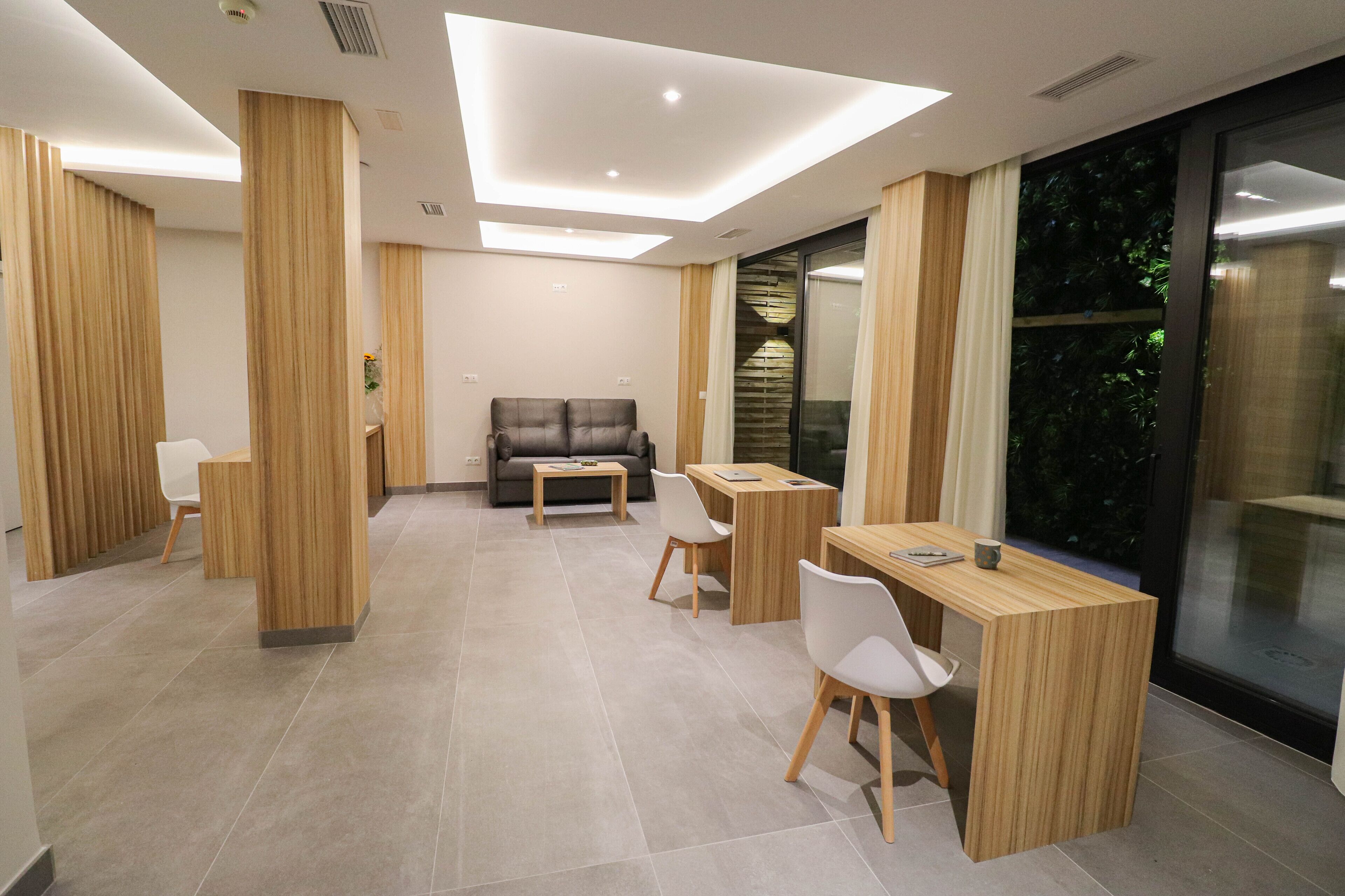Une chambre d’hôtel moderne dotée d’un coin repas, d’un canapé et d’une grande fenêtre donnant sur un paysage verdoyant.