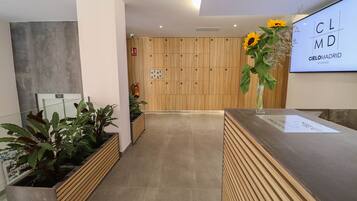 A reception area with a wooden reception desk, a large screen displaying 'CIELOMADRID STUDIOS', and a fire extinguisher on the wall.