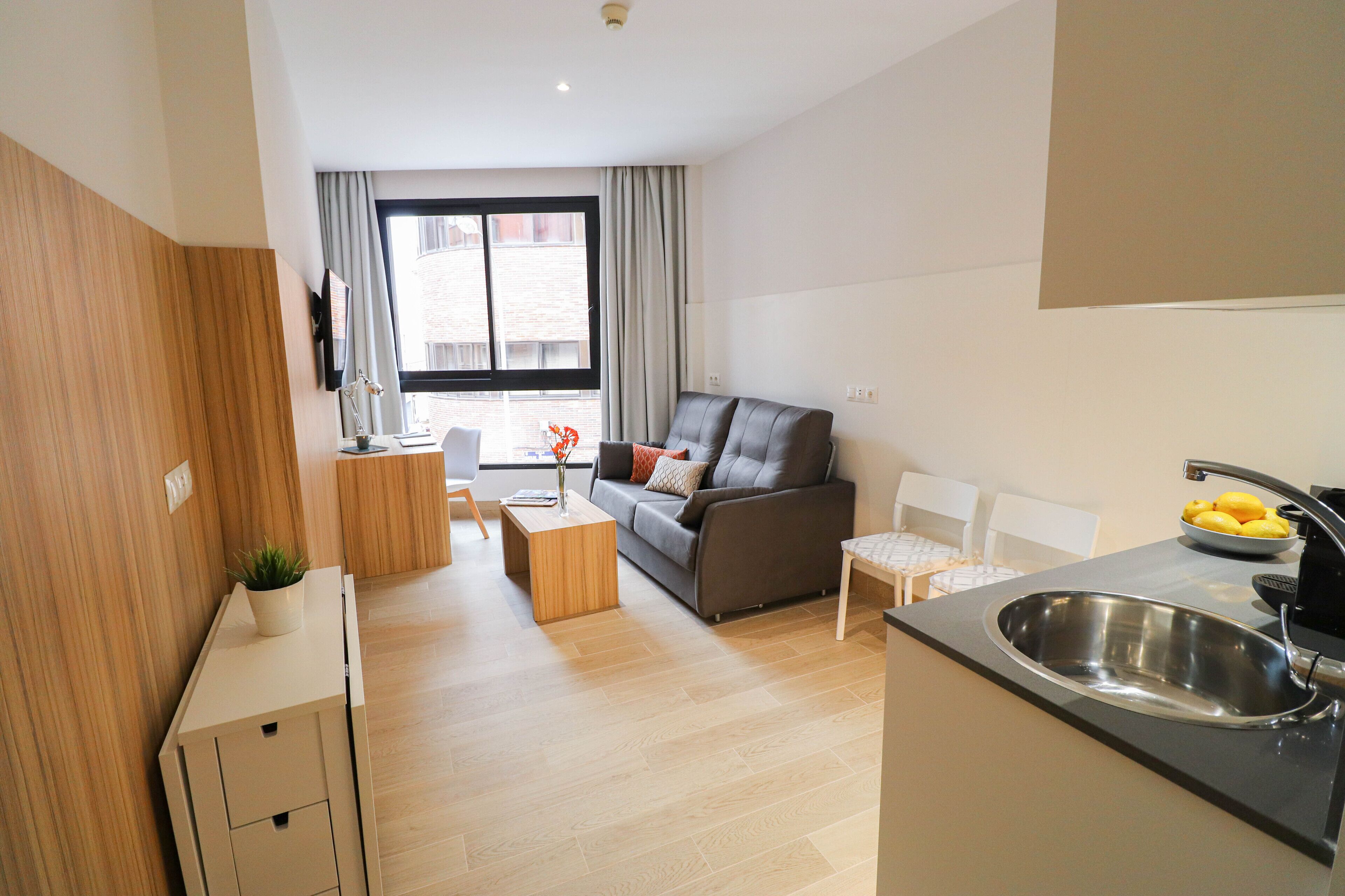 Een modern appartement met een zithoek, kitchenette en stadszicht.