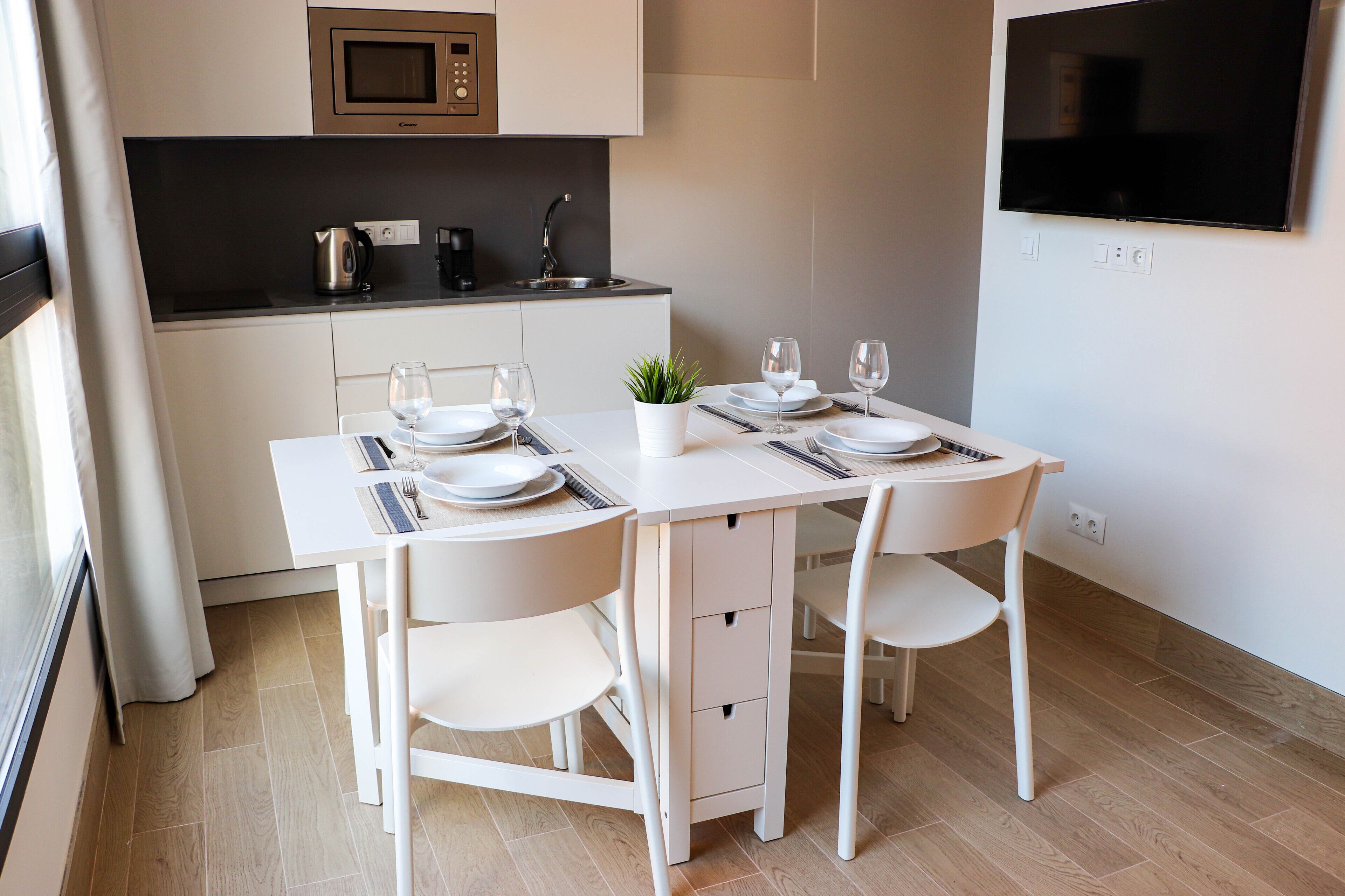 A modern kitchen with a microwave, sink, and a flat-screen TV.