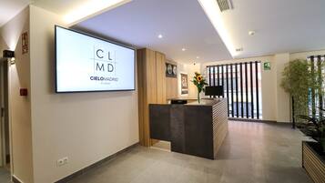 A modern reception area with a large screen displaying 'Cielomadrid Studios' and a reception desk.
