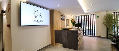 A modern reception area with a large screen displaying 'Cielomadrid Studios' and a reception desk.