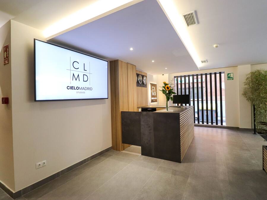 A modern reception area with a large screen displaying 'Cielomadrid Studios' and a reception desk.
