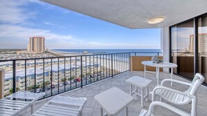 A balcony with white furniture, a view of the beach, and high-rise buildings in the distance. - Wake up to beautiful ocean views!!! (MYRTLE BEACH)