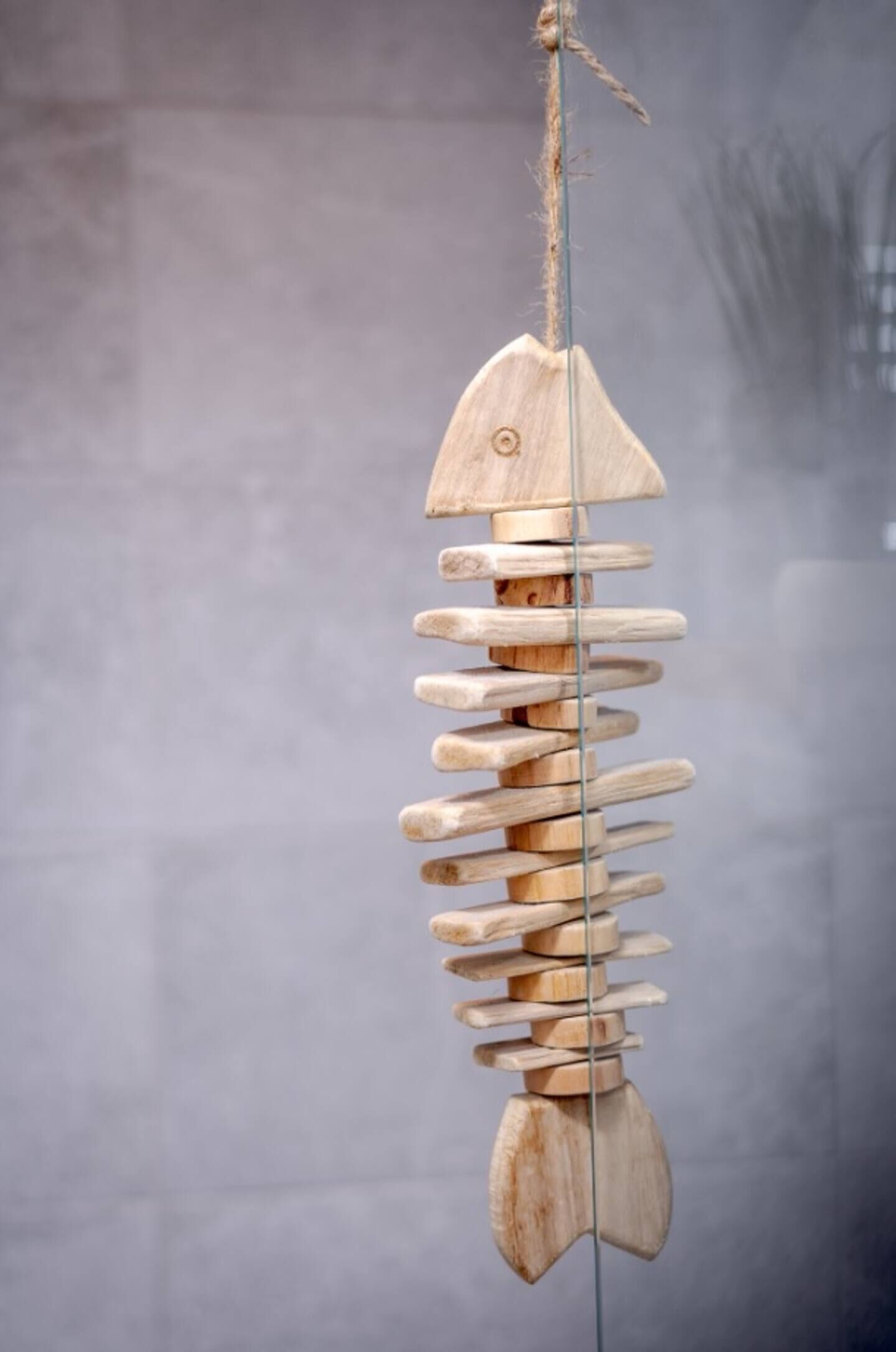 Un móvil de madera con forma de pez colgando de un hilo.