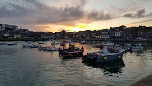 A harbor at sunset with boats docked and buildings in the background.