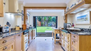 A modern kitchen with wooden cabinets, a large island, and a view of a garden.