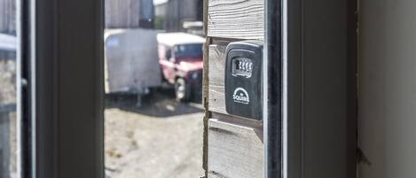 A door with a security keypad and a view of a parking area with vehicles.