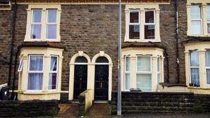 A two-story stone house with a traditional design, featuring a central entrance with a black door, white-framed windows, and a small porch area. - Karah Suites - Church Road I (Bristol)
