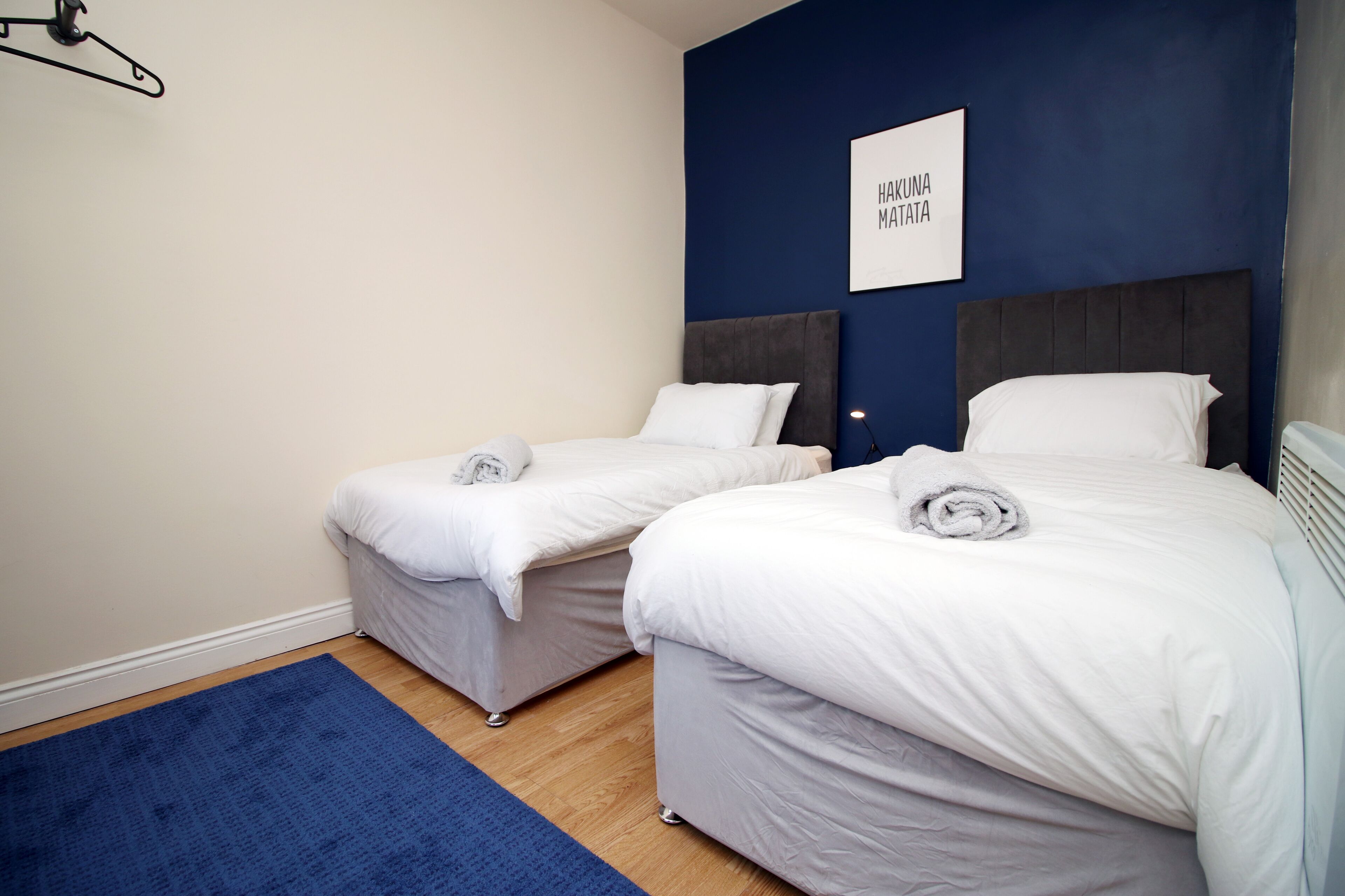 Quarto de hotel com duas camas, um tapete azul e uma placa na parede.