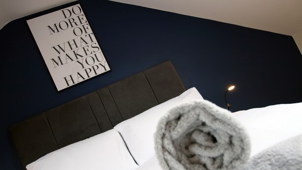 A neatly made bed with a rolled-up towel and a motivational quote on the wall. - Karah Suites - Church Road I (Bristol)