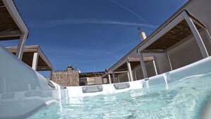 A hot tub area with clear blue water, surrounded by white structures with wooden beams. - Dimora Assuntina Fine Rooms (Martano)