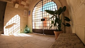 An arched doorway with a barred window, a potted plant, and a tiled floor. - Dimora Assuntina Fine Rooms (Martano)