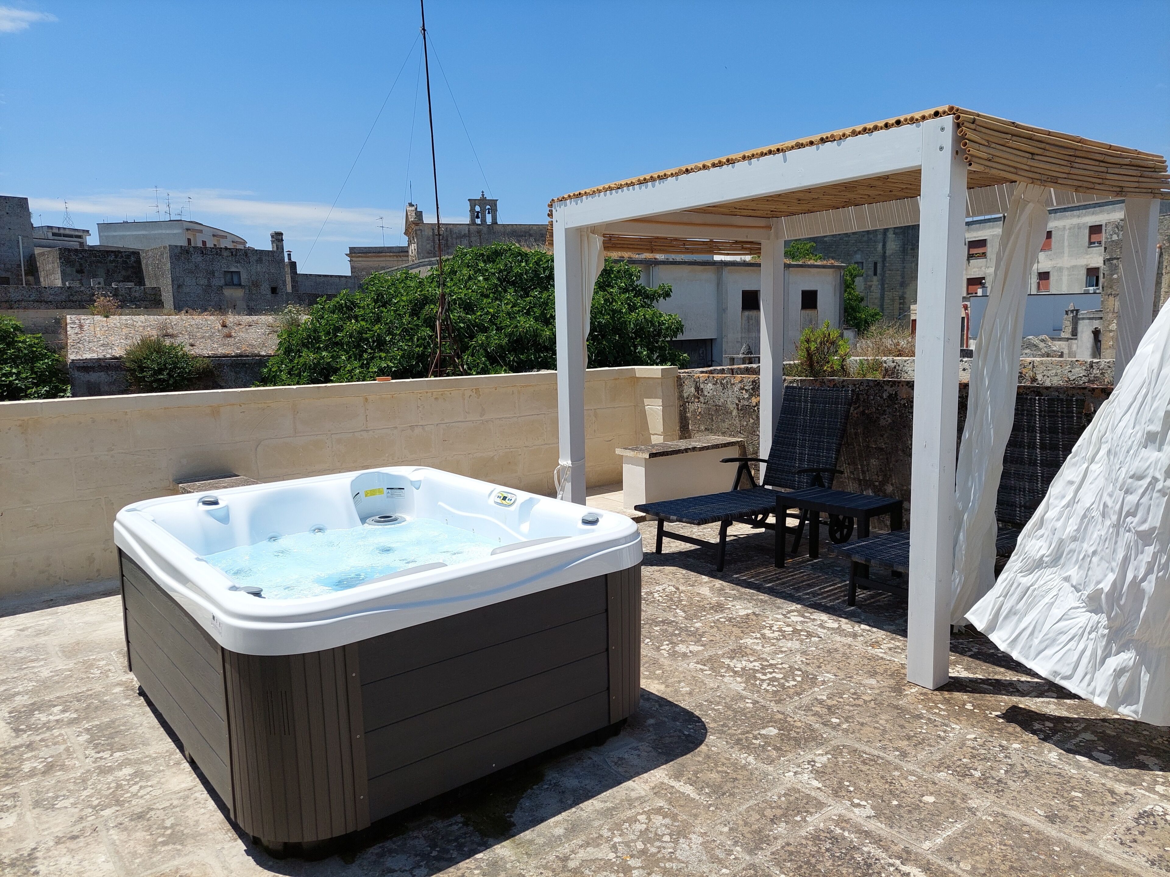 Een dak terras met een hottub, zitplaatsen buiten en een pergola.