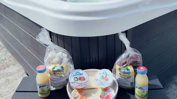 A hot tub with a table in front, holding food items and drinks.