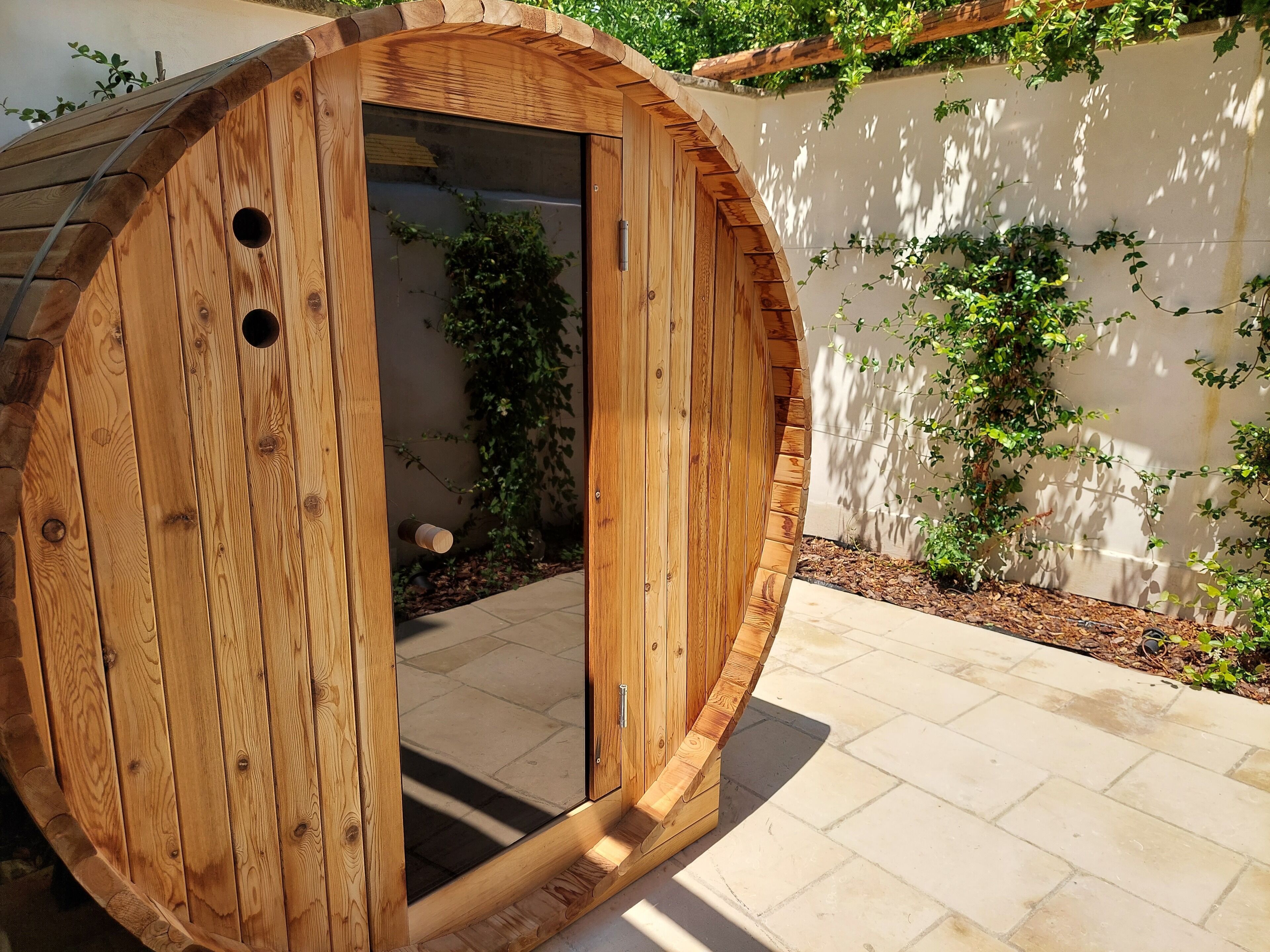 Een houten sauna met een rond ontwerp, een deur en een klein raam.
