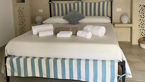 A bed with a striped bedspread, multiple pillows, and neatly folded towels. - Dimora Assuntina Fine Rooms (Martano)