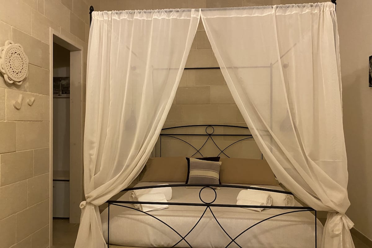 A bed with a metal frame and white bedding, covered by a white canopy.