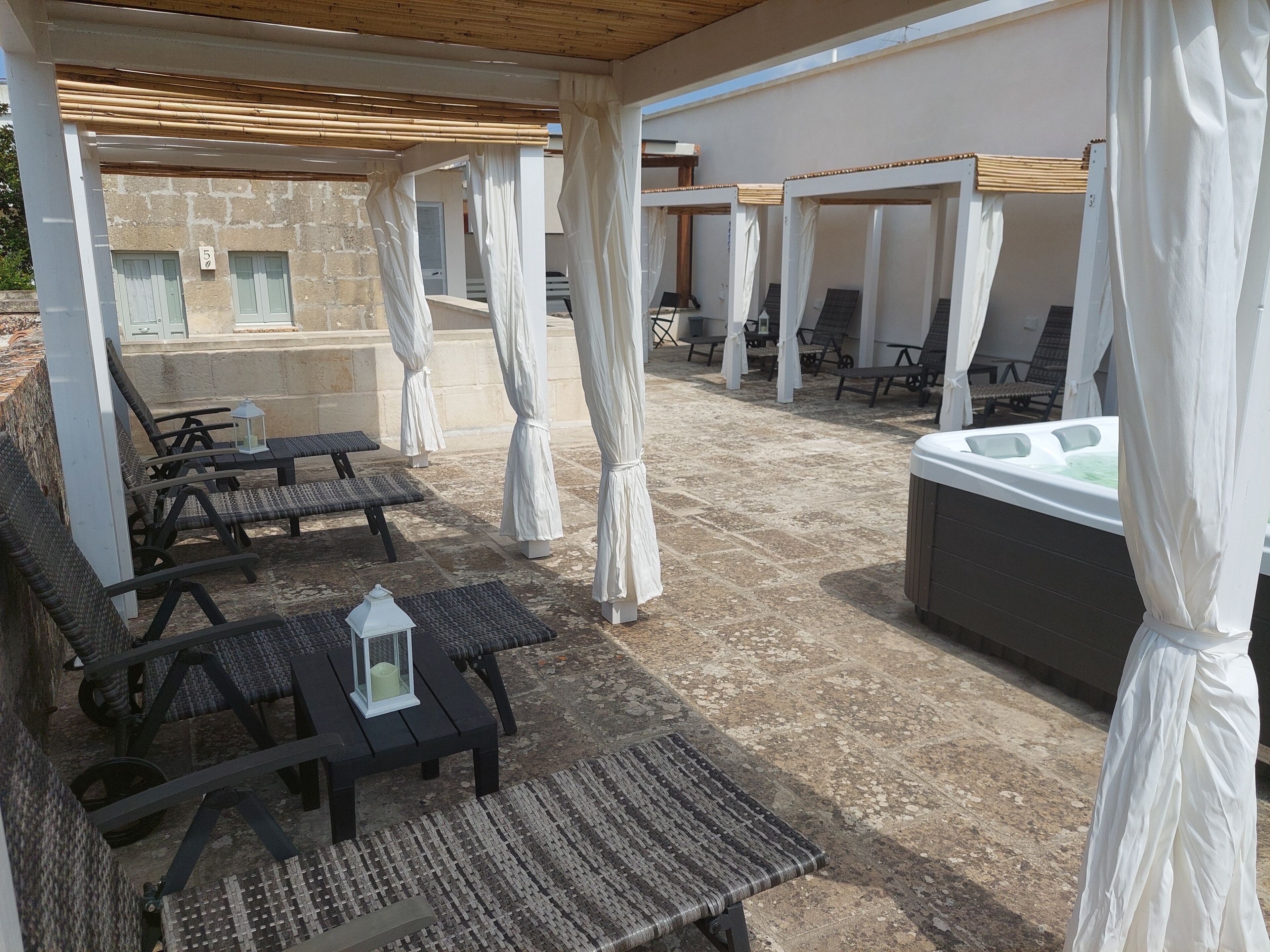 Uma área externa com assentos de lounge e uma banheira de hidromassagem.