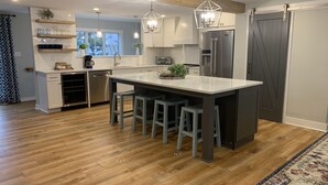 Une cuisine moderne dotée d’un îlot central, de tabourets de bar, d’un plancher en bois et d’un dosseret de carreaux disposés en motif chevrons.