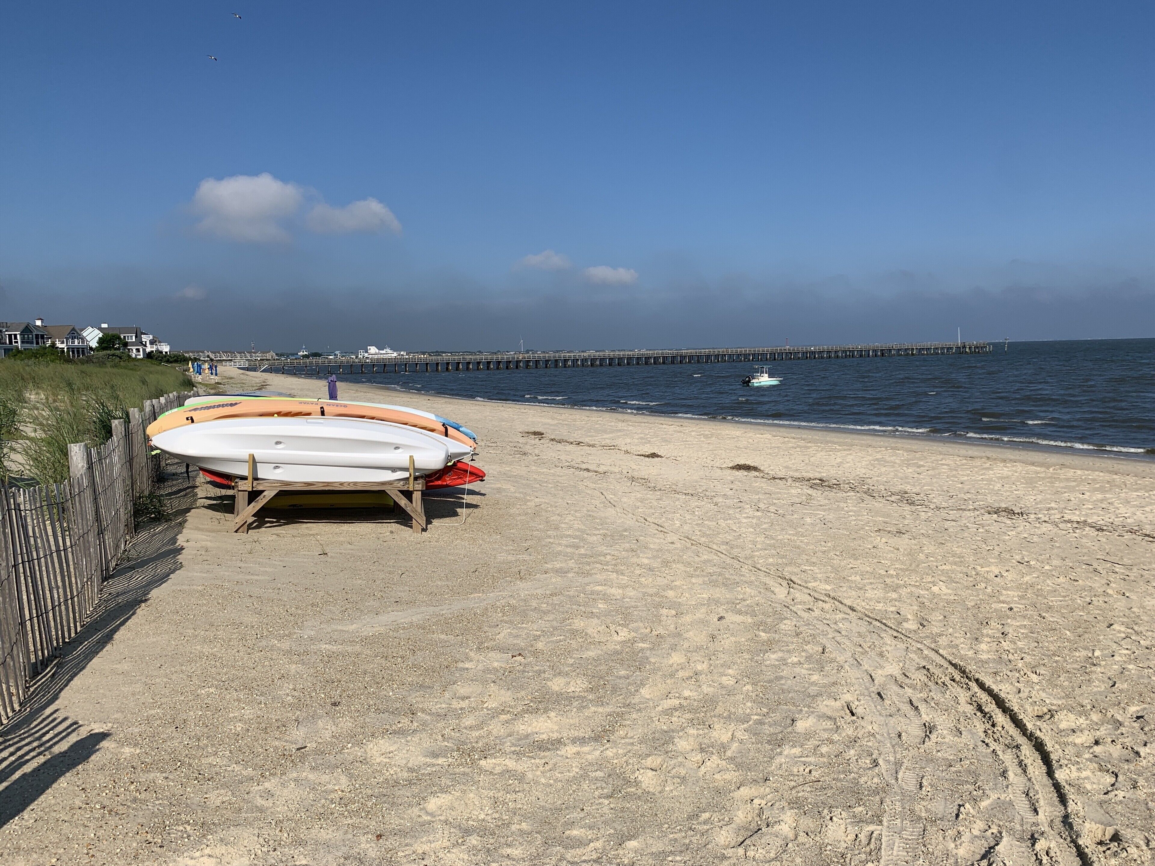 Une plage de sable bordée d’une clôture en bois et où se trouvent plusieurs postes de surveillance des sauveteurs.