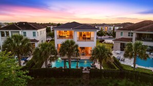A two-story house with a swimming pool, surrounded by palm trees and other houses. - Chic Mansion with Games Room (Kissimmee)