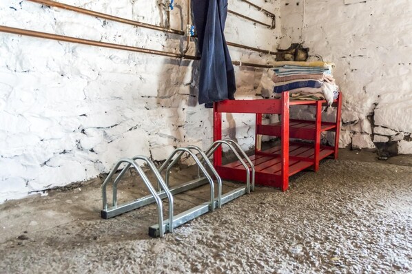 A room with a red metal shelf unit, a metal ladder, and a white brick wall. - Ashgrove Farm - 1 Bedroom Apartment - Llawhaden (Narberth)