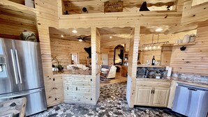 Interior de una cabaña de madera con cocina, comedor y sala de estar.