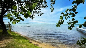 Vista de un lago con un muelle que se adentra en el agua, rodeado de zonas verdes y árboles.