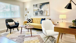 Un salon moderne comprenant un canapé, des fauteuils, une table basse et un bureau avec une lampe.