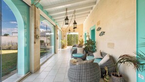 A covered outdoor seating area with wicker furniture and potted plants. - Tenuta Donna Caterina by BarbarHouse (Mesagne)