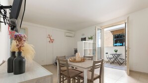 Un espace de salle à manger moderne avec une table et des chaises en bois, un meuble blanc et un vase contenant des fleurs séchées.
