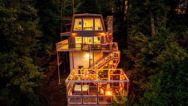 Eine mehrstöckige Holzhütte mit Glasgeländern, umgeben von dichtem Wald.
