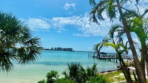 A coastal view with clear turquoise water, palm trees, and a distant city skyline. - Lovers Key Beach Club 1105 - Private Beach (Bonita Springs)