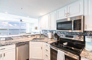 A modern kitchen with white cabinetry, a stainless steel stove, and a built-in microwave.