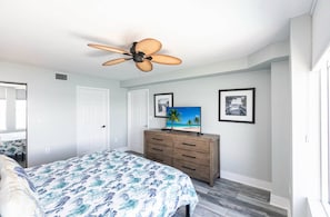 A bedroom with a bed, a ceiling fan, a dresser, and framed pictures on the wall. - Southern Comfort - Updated Waterfront Condo (Bonita Springs)