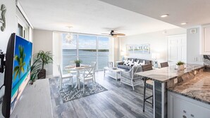 A modern kitchen with a large island, white cabinetry, and a view of the ocean.