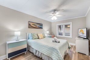A bedroom with a bed, bedside tables, a ceiling fan, a window with a view, and a TV. - ⭐️White Marlin 107 Epic Renovation Bayfront Sunsets Pool ⭐️ (Ocean City)