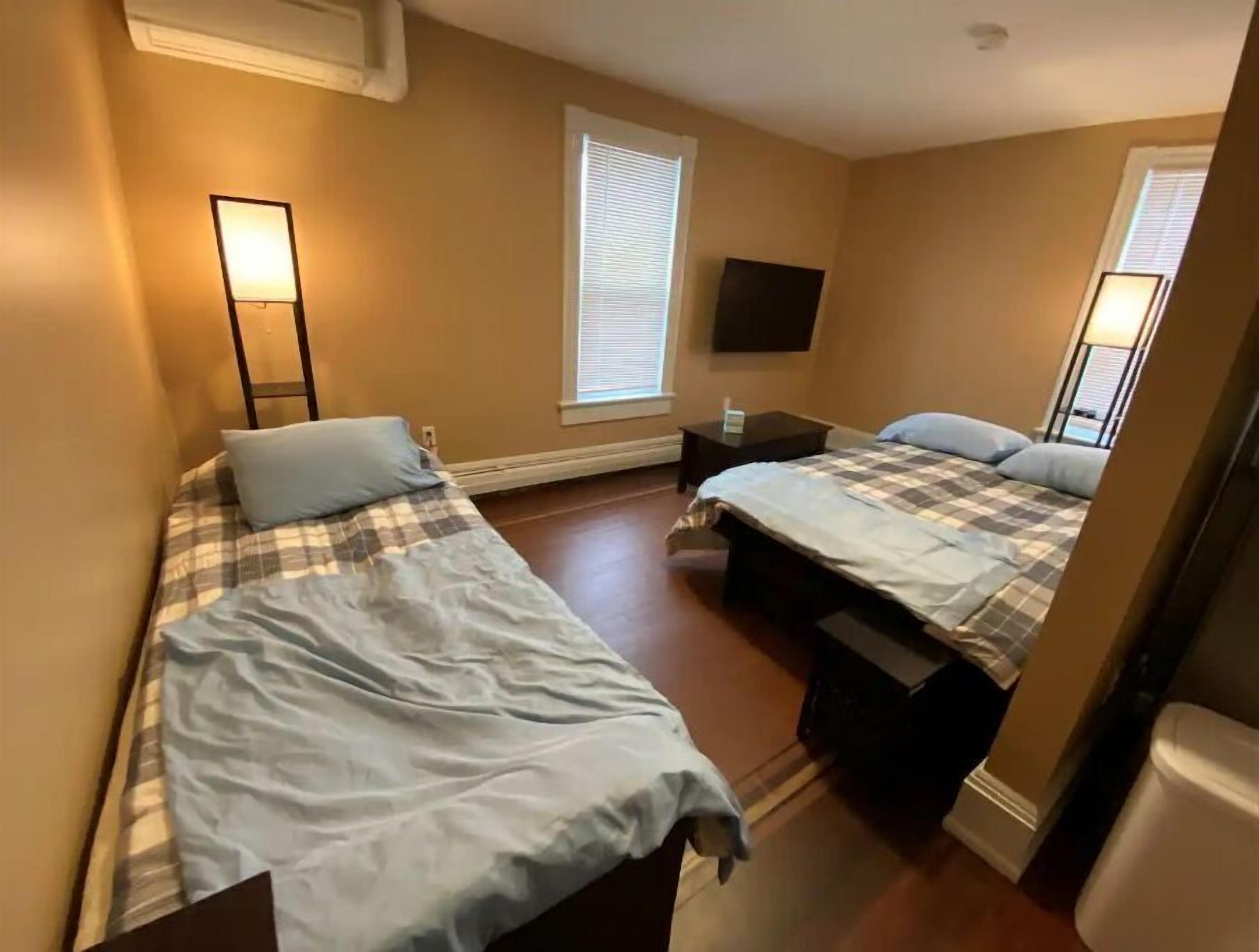 A bedroom with two beds, a flat-screen TV, and a bedside table.