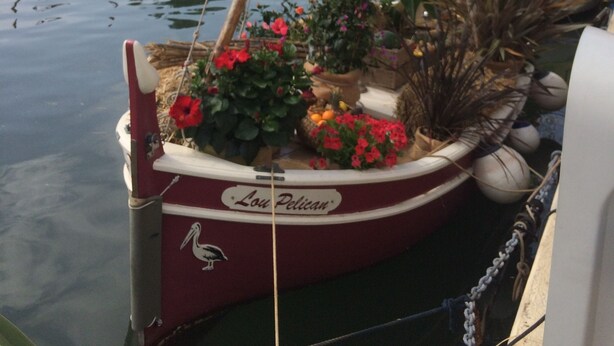 A boat docked at a marina with a name "Lou Pelican" and surrounded by other boats and buildings. - Cosy studio for 2 near the beach (Sanary-sur-Mer)