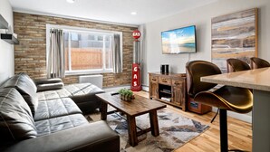 Een moderne woonkamer met een leren bank, een houten salontafel, een televisie en een open haard.