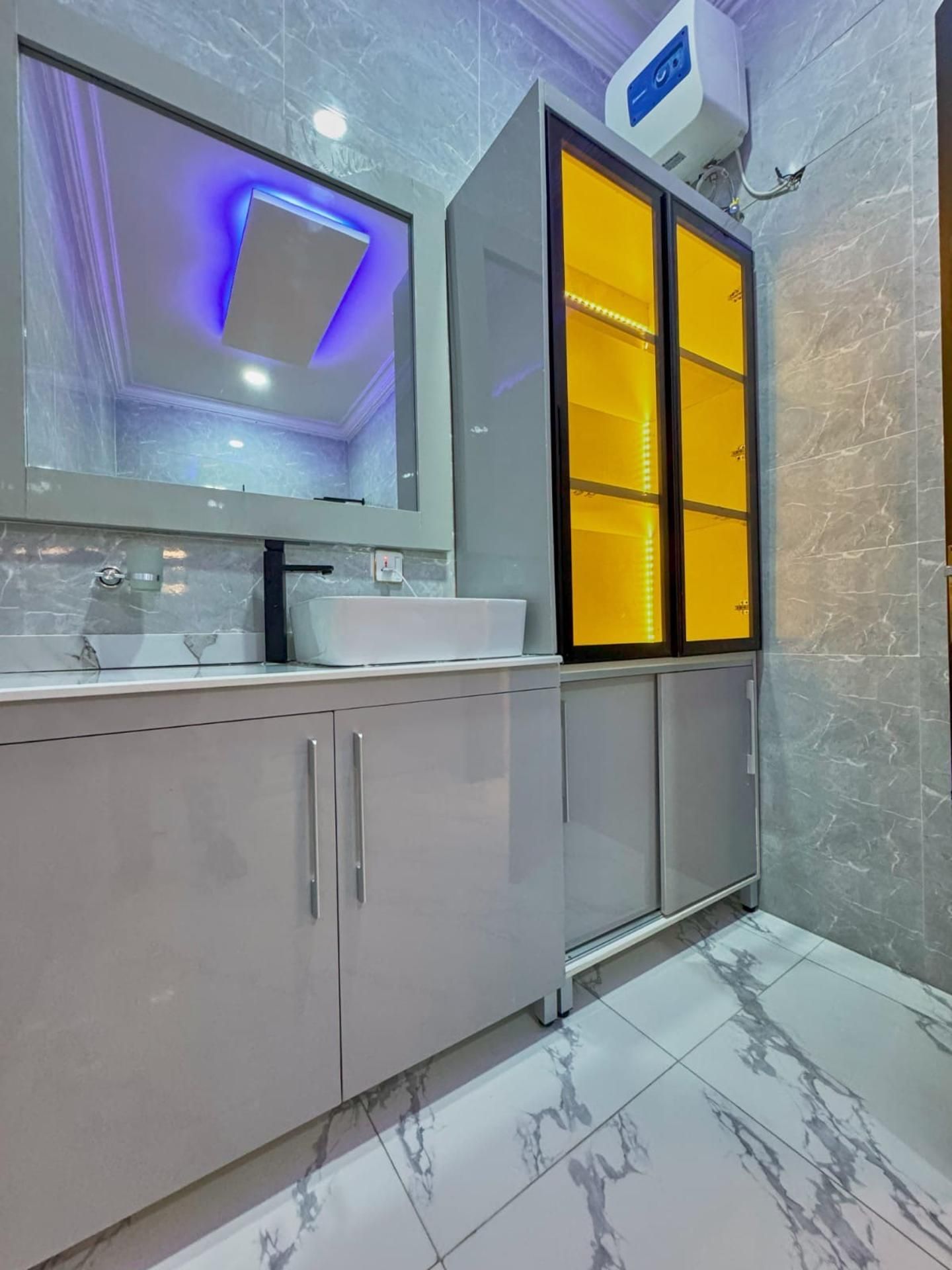A modern bathroom with a large mirror, a sink, and a cabinet with a glass door.