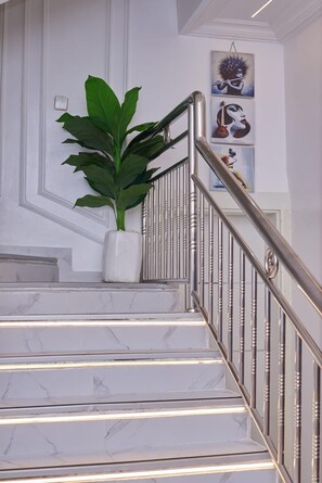 A staircase with marble steps and a metal railing, a potted plant, and artwork on the wall. - 3 Bedrooms Villa Duplex in Lekki Lagos Nigeria (Lekki)
