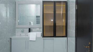 A modern bathroom with a grey marble wall, a white sink with a towel, and a black door with a keyhole.