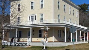 A two-story building with a covered porch and a sign for Lake Gomser Hotel. - Apt 3C Lake Bomoseen Inn “The Dog” with boat slip.  (Castleton)