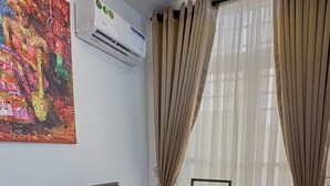 A dining area with a glass table, four chairs with patterned upholstery, a potted plant, and a colorful abstract painting on the wall. - 1 Bedroom Ensuite in a Shared House (Lekki)