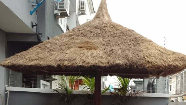 A patio area with a thatched umbrella, red chairs, and a small table. - 5 Bedrooms Einsuite House in Lekki Lagos Nigeria (Lekki)